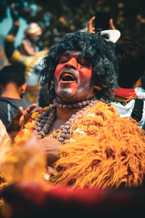 Free Vibrant festival performer in traditional attire in Varanasi, India, with garlands and face paint. Stock Photo