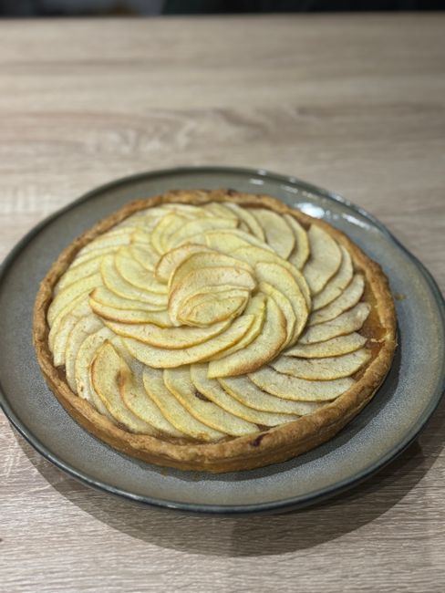 A golden lattice-topped apple pie cooling on a wire rack with a slice cut out, showing thick spiced apple filling and a flaky crust.