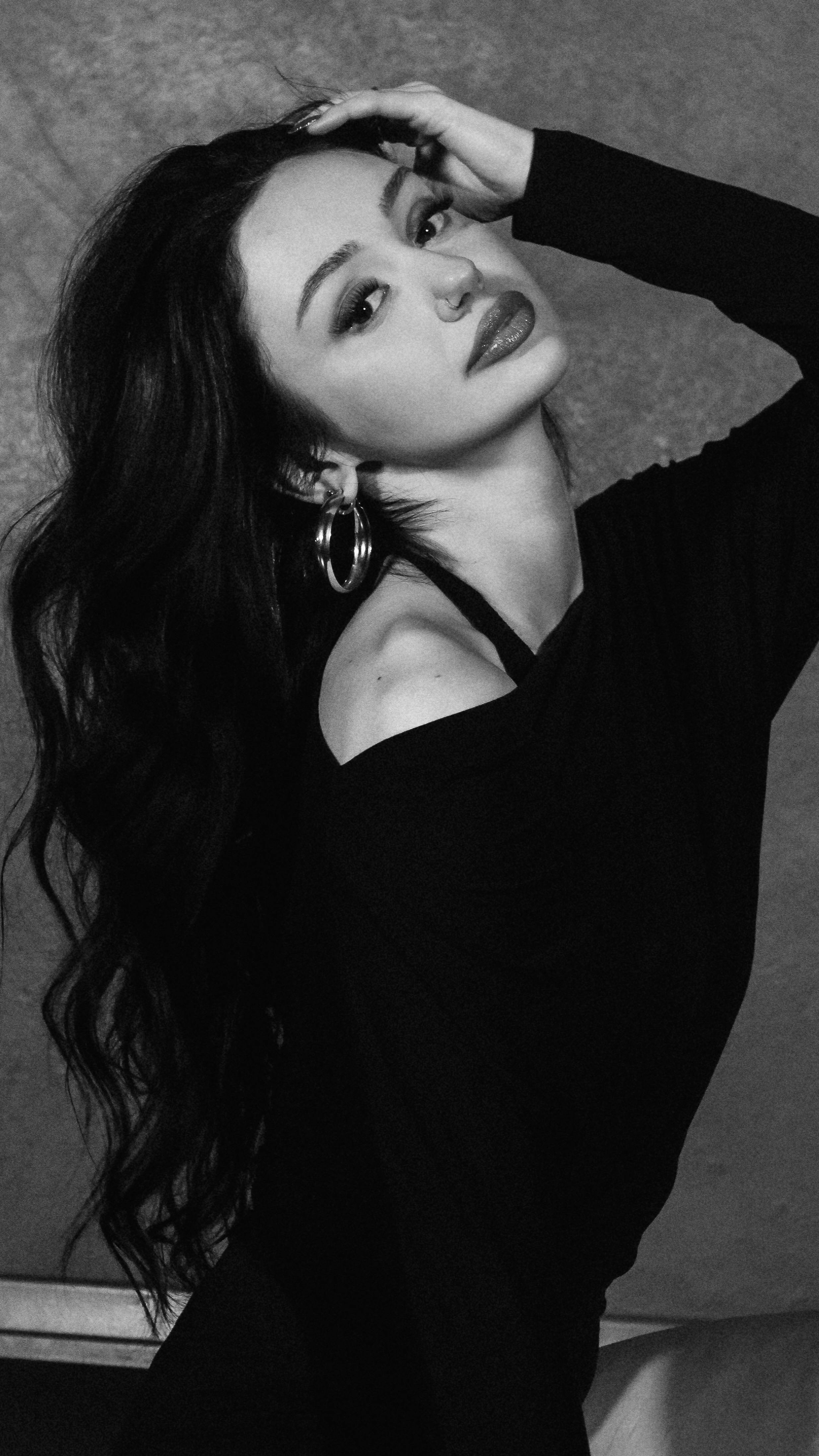 Stylish black and white portrait of a woman with long hair and hoop earrings.