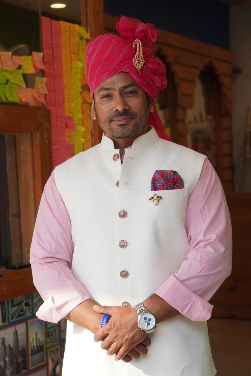 Free Man in traditional Indian attire with a pink turban standing indoors, showcasing cultural fashion. Stock Photo