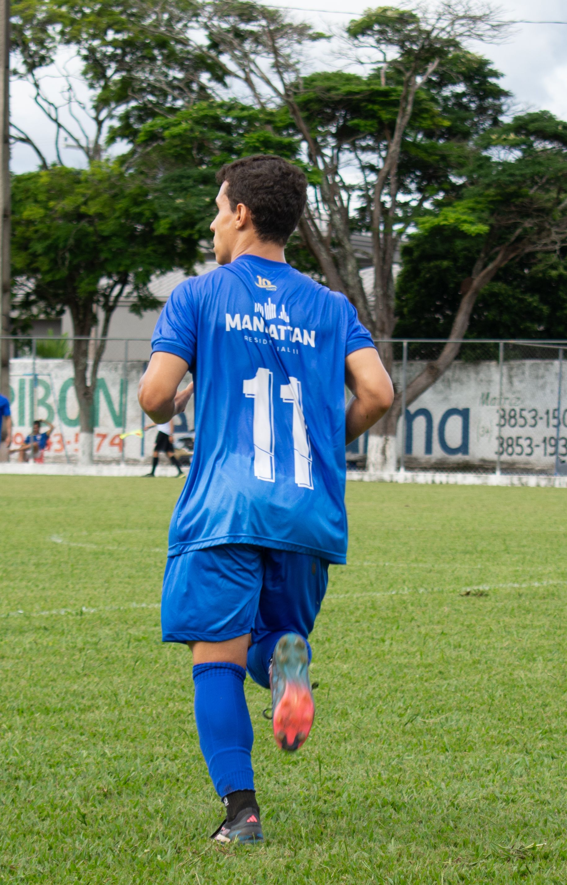Soccer player in blue jersey number 11 running on outdoor field during daytime match.
