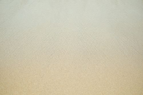 Free Minimalistic view of a sandy beach and calm sea, perfect for backgrounds and relaxation themes. Stock Photo