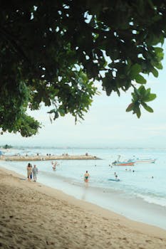A lively tropical beach scene with tourists enjoying the sun and water activities.