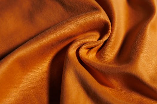 Detailed close-up of an orange fabric swirled into a soft fold, showcasing its texture.