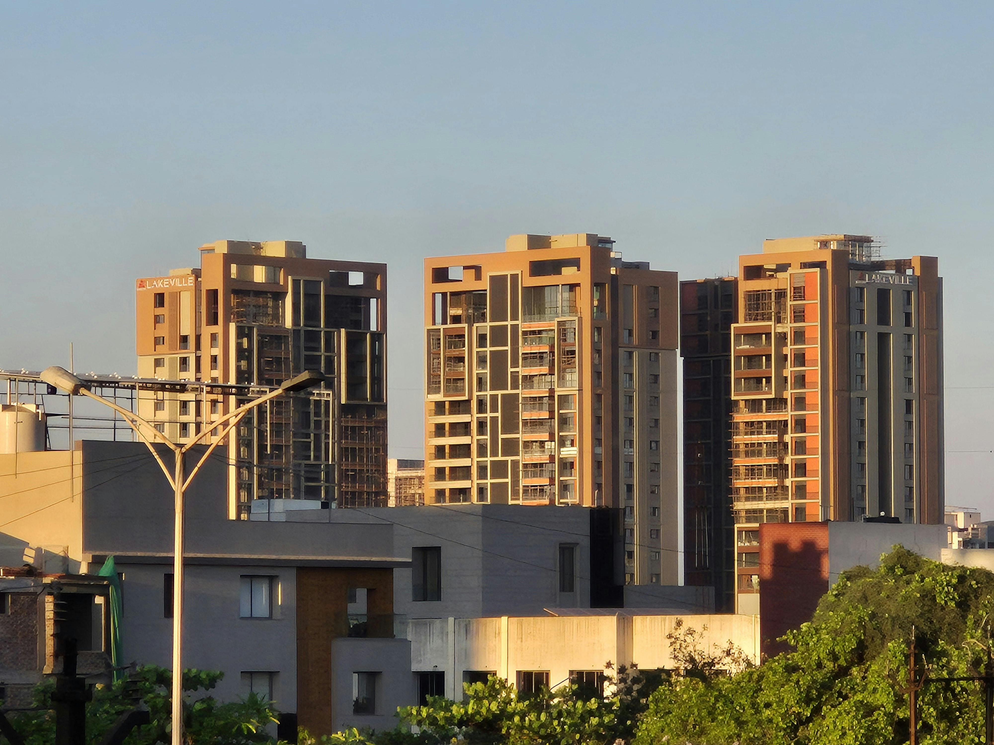 Gratis Gedung-gedung pencakar langit kontemporer di Surat, India, diabadikan saat matahari terbenam dengan langit cerah. Foto Stok