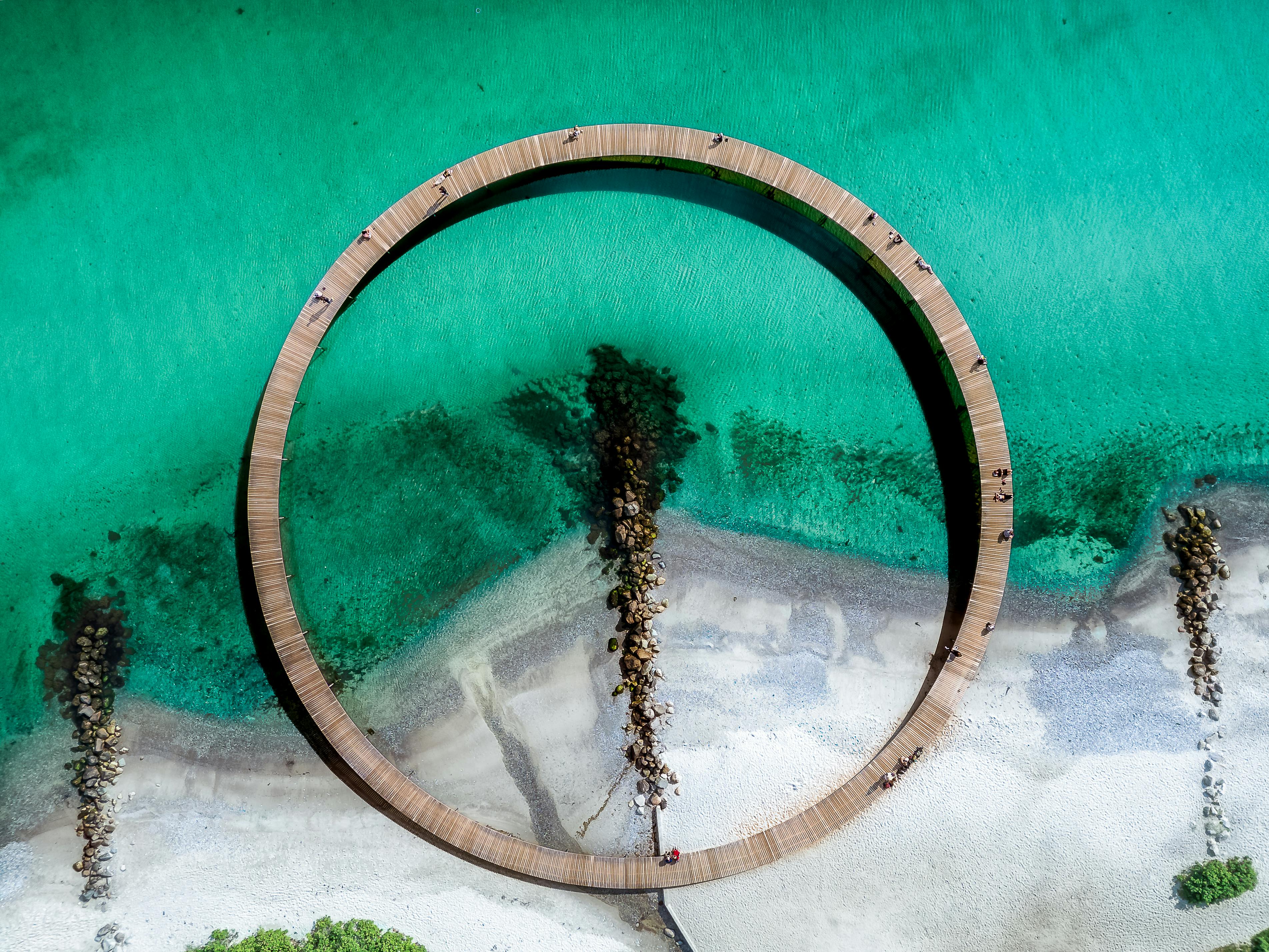 Stunning aerial view of the Infinite Bridge in Aarhus, Denmark, surrounded by turquoise sea and sandy beach. - Aarhus