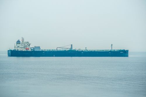 Free A solitary cargo ship sails across a serene ocean, creating a peaceful maritime scene. Stock Photo