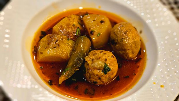 Delicious vegetarian curry featuring potatoes, spicy peppers, and dumplings in rich sauce.