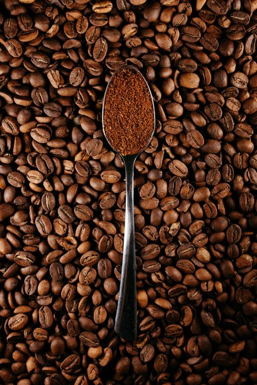 Free Top view of a spoon with ground coffee on a bed of whole coffee beans. Stock Photo