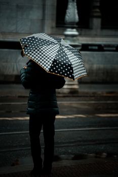 A solitary figure with polka dot umbrella on a rainy Dublin street, capturing a moody atmosphere.