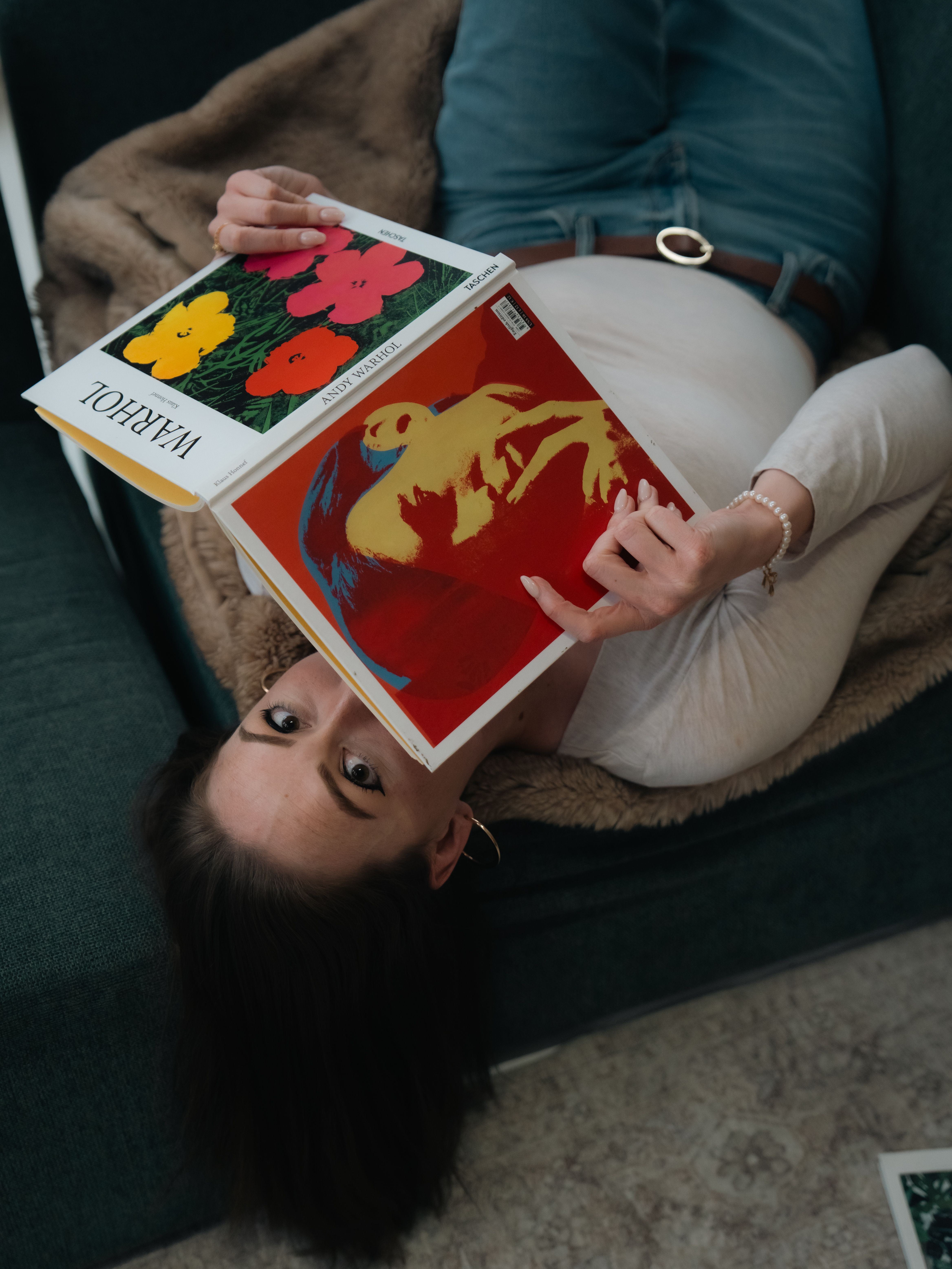 Casual woman reading Andy Warhol art book on a cozy sofa in Chicago.