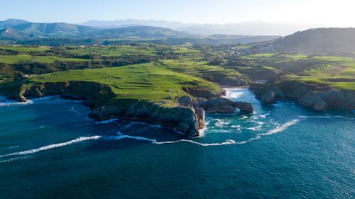 Free Breathtaking aerial view of Asturias coastline with lush greenery and blue ocean waves. Stock Photo