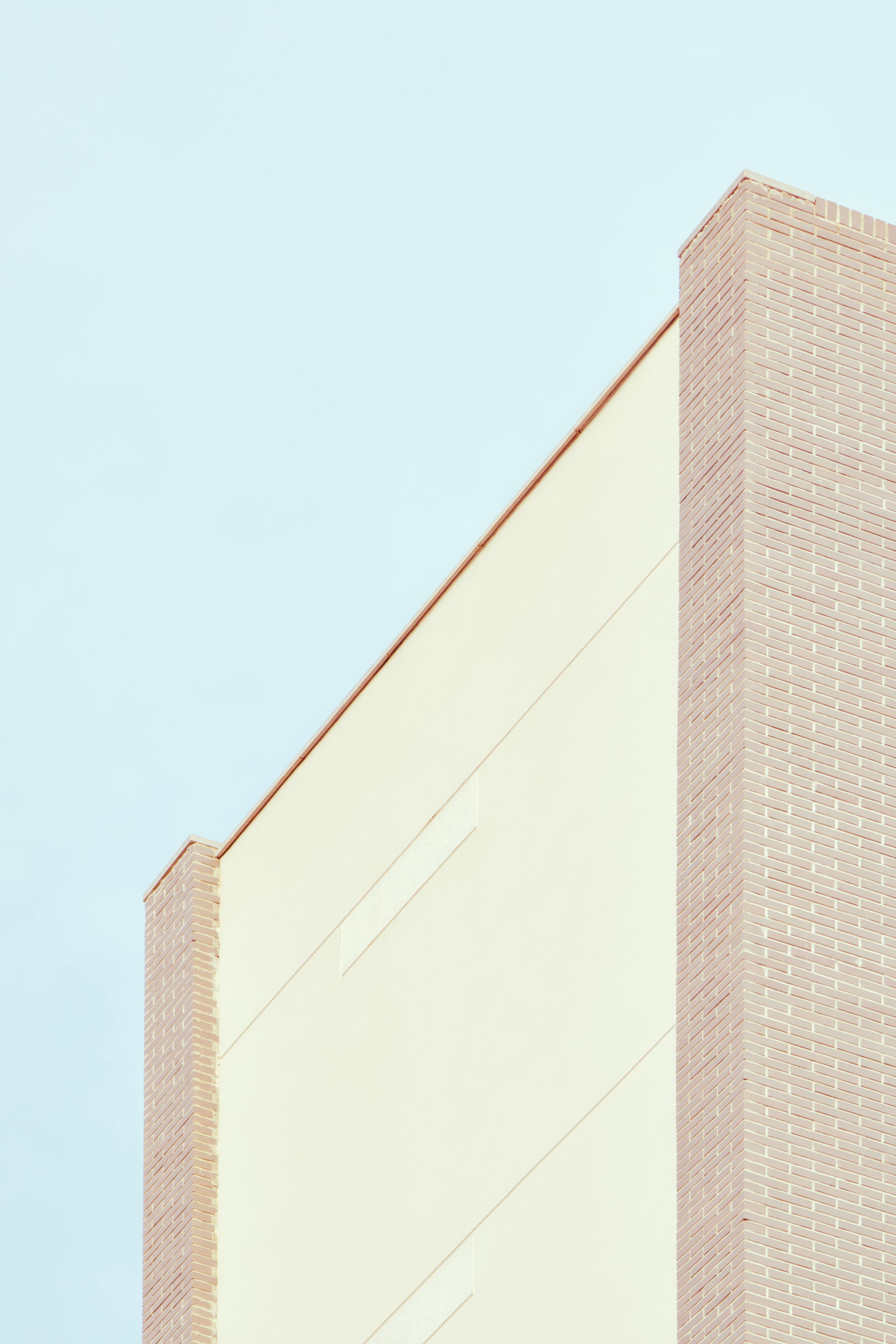 Ilmainen Lähikuva korkean tiilirakennuksen julkisivusta Torreviejassa, jossa on puhtaat linjat ja sininen taivas taustalla. Kuvapankkikuva