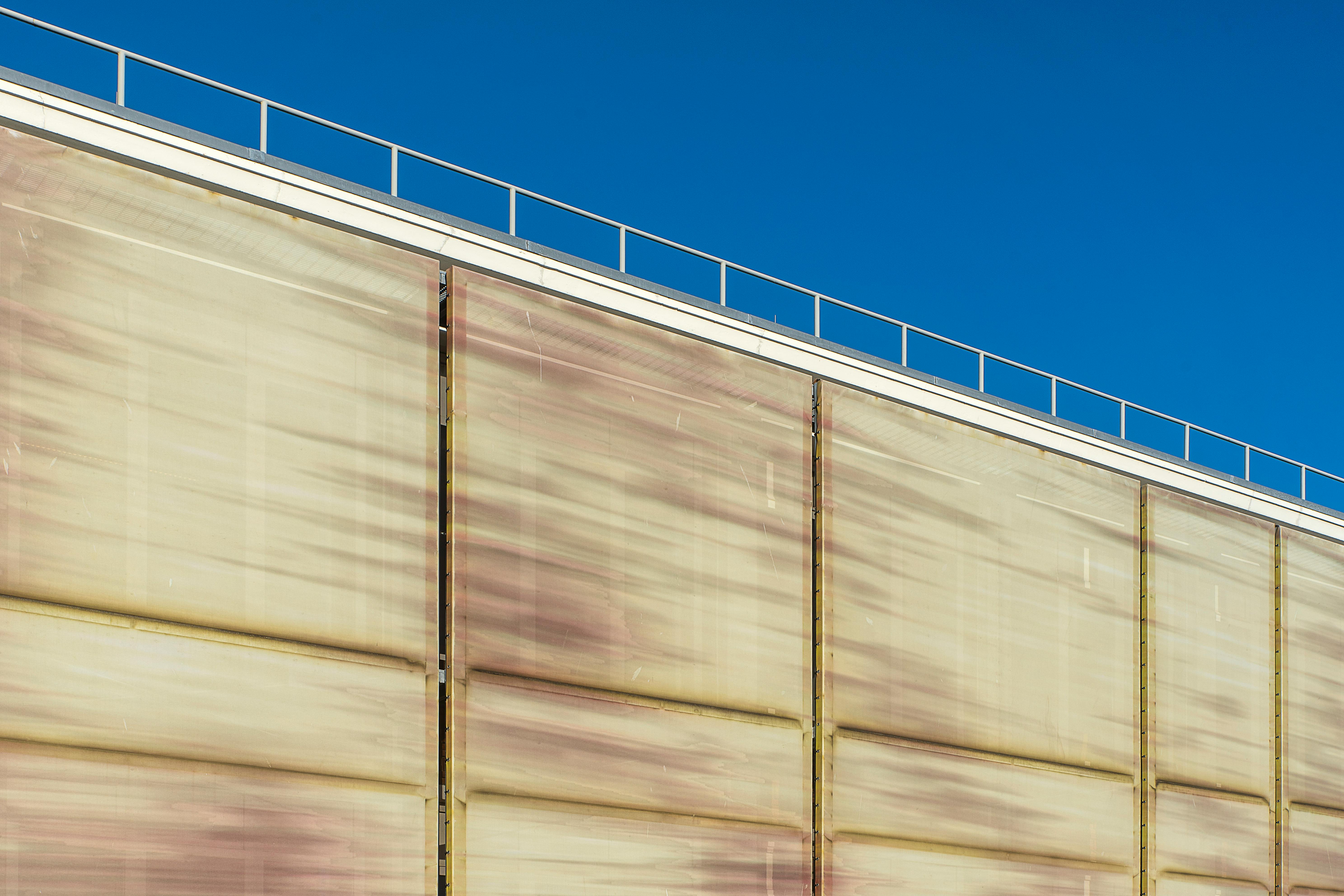 Free Close-up of an industrial building's rustic metal facade under a clear blue sky. Stock Photo