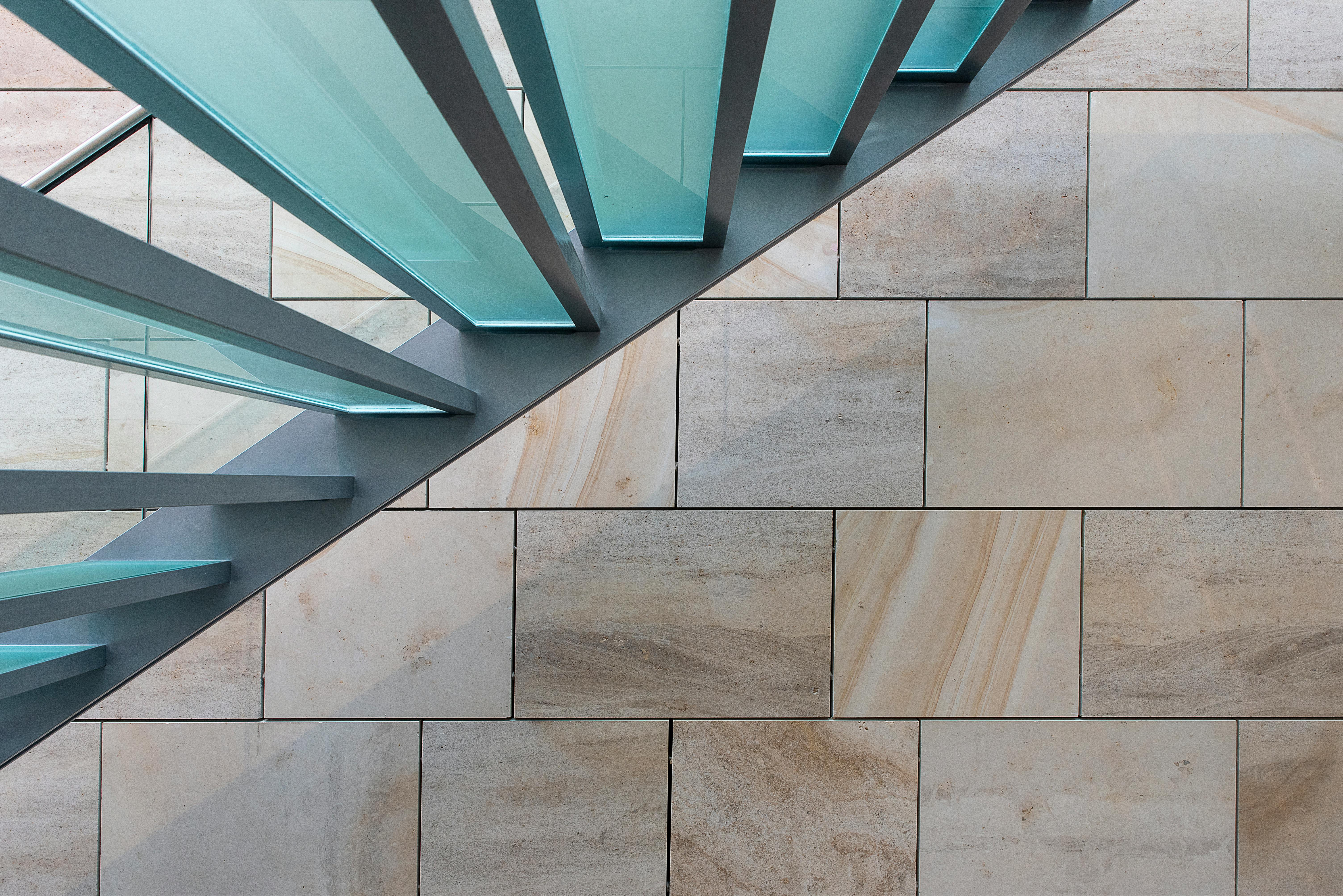 Gratis Tampilan dari atas sebuah tangga modern dari kaca dan logam di atas lantai keramik, menampilkan desain geometris yang tajam. Foto Stok