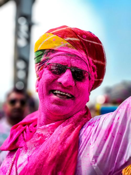 Free Man covered in pink powder celebrating Holi festival, smiling joyfully outdoors. Stock Photo
