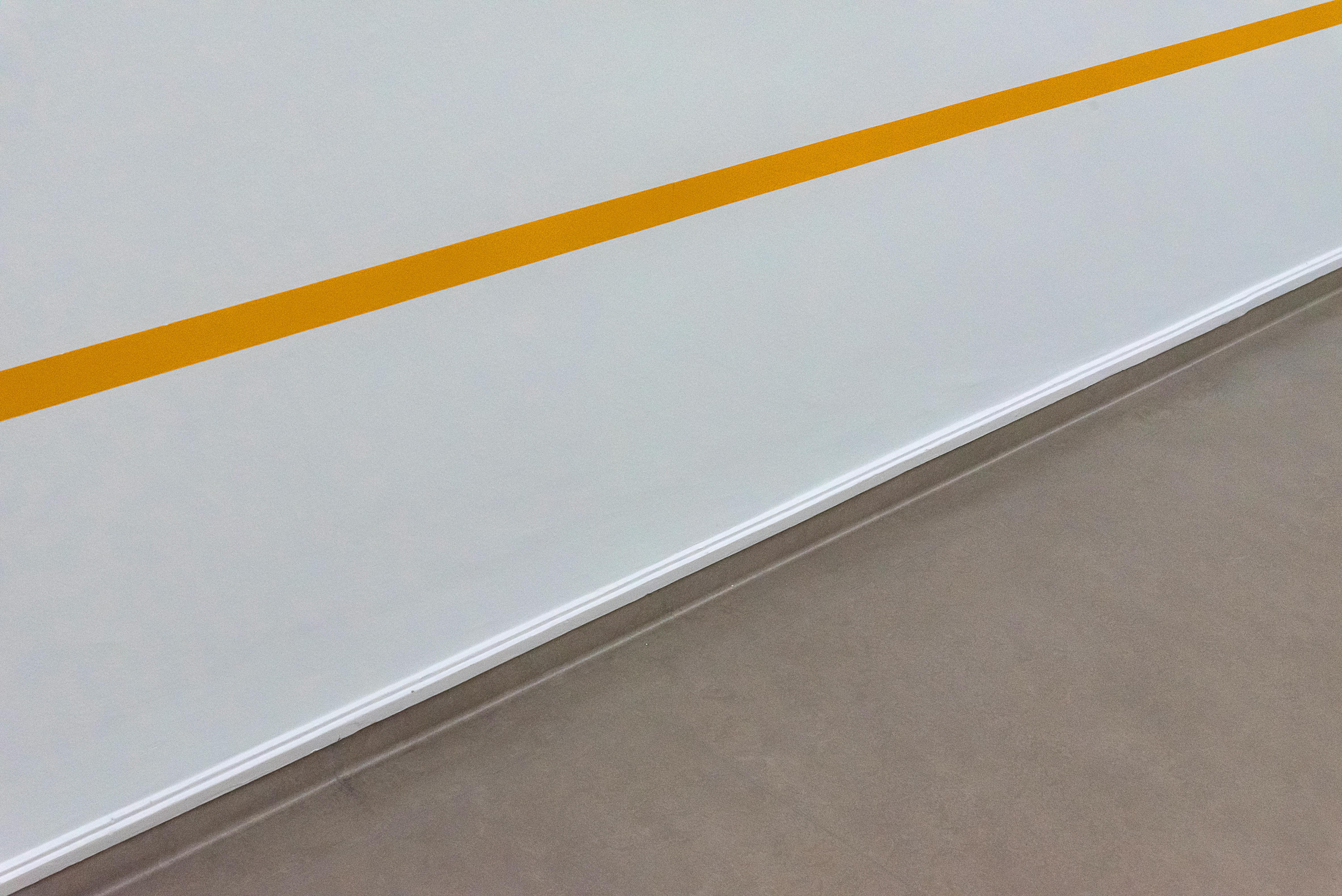 Bezpłatne Proste i nowoczesne, minimalistyczne wnętrze z ukośną żółtą linią na białej ścianie. Zdjęcie z galerii