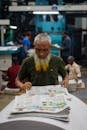 Elderly Man Reading Newspaper in Printing Press