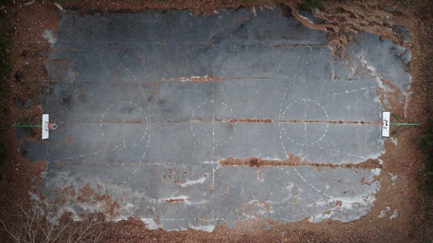 Aerial shot of an empty, dilapidated basketball court surrounded by nature in Ravne na Koroškem, Slovenia.