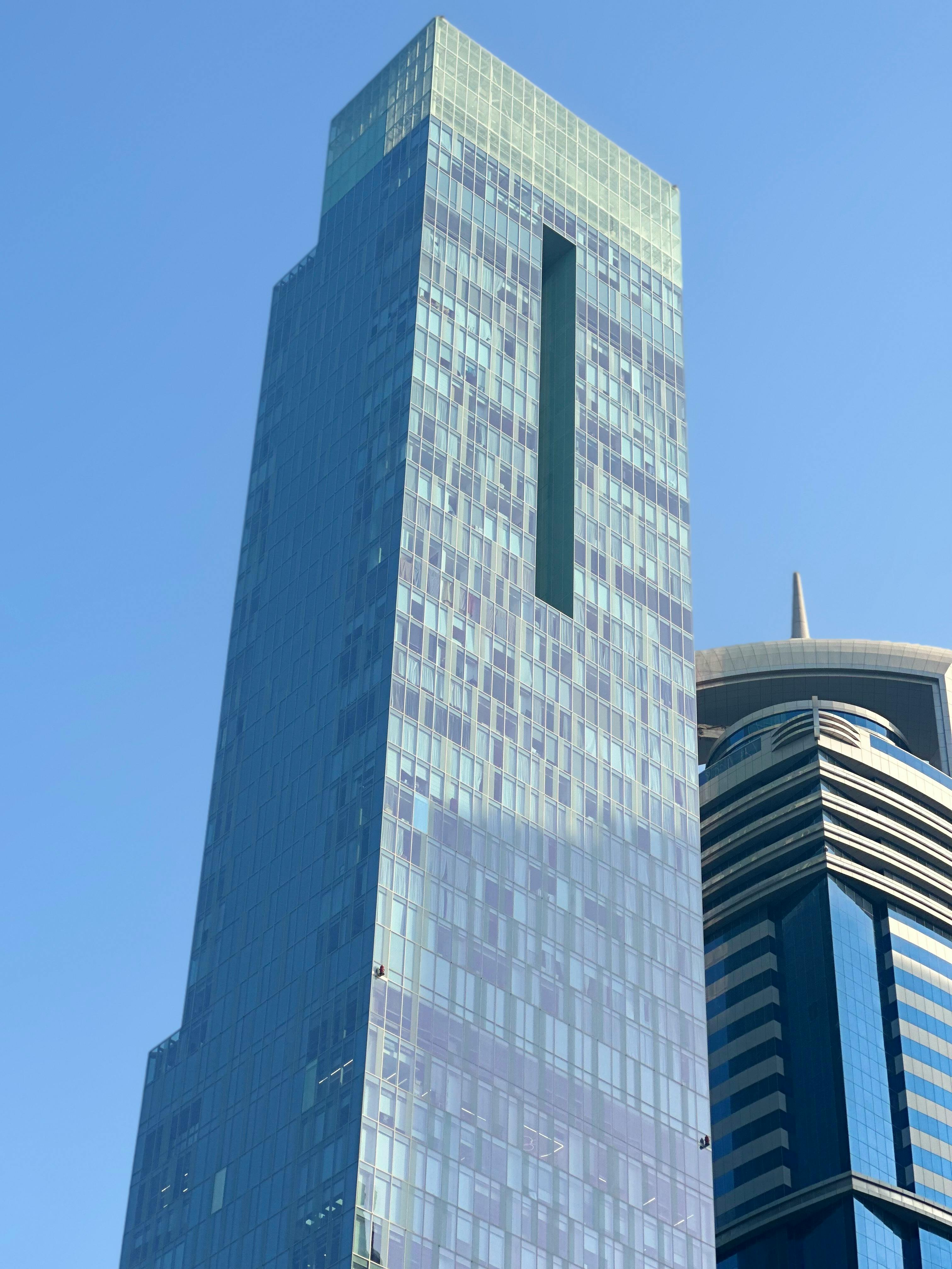 無料 賑やかな都会の風景の中で光を反射するモダンなガラス張りの超高層ビル。 写真素材