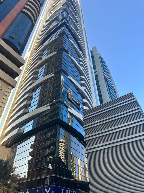 Free Tall skyscraper in Dubai with reflective glass facade, capturing modern architecture under clear blue sky. Stock Photo