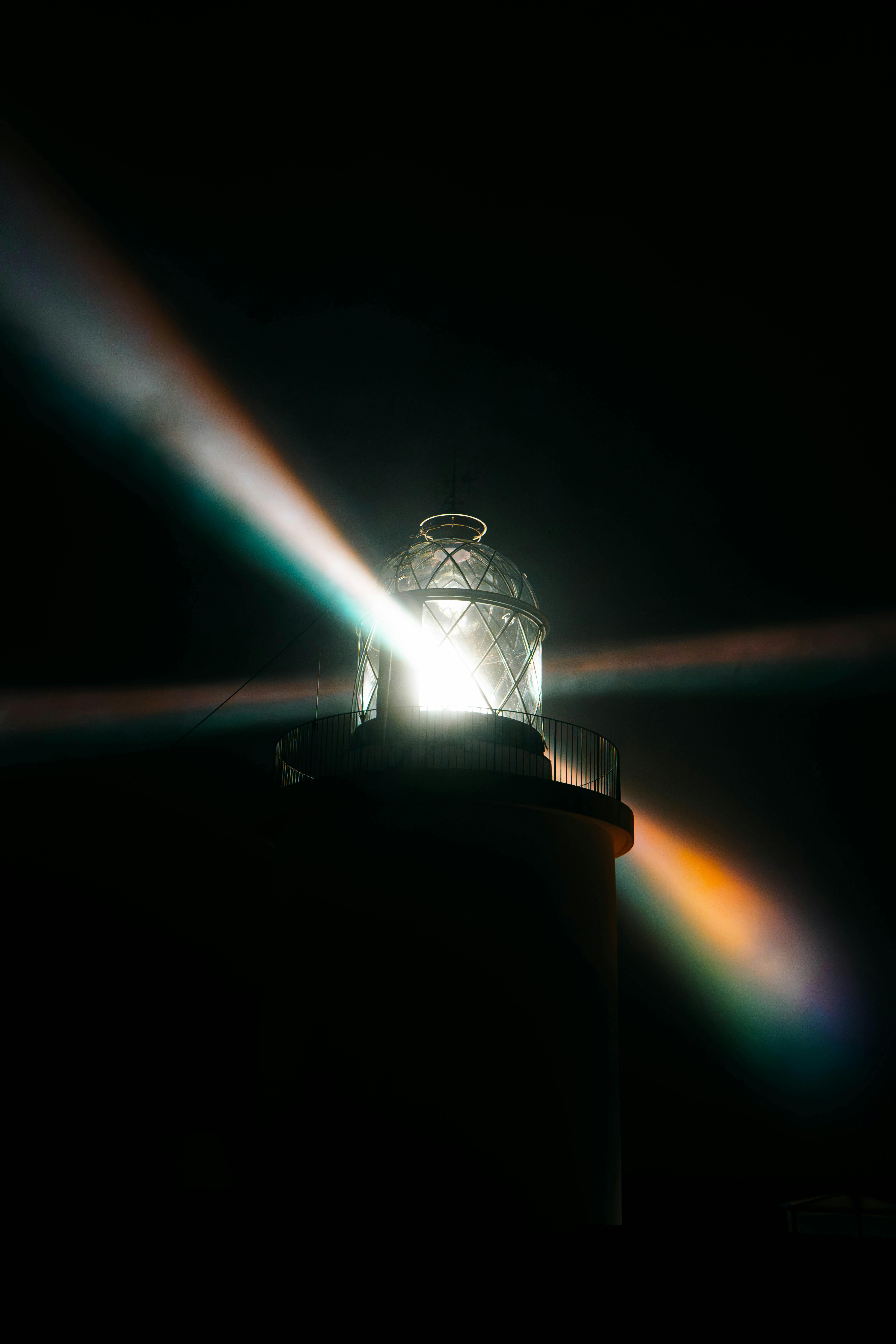 Ücretsiz Geceleyin göz alıcı ışık huzmeleri saçan bir deniz feneri, çarpıcı bir etki yaratıyor. Stok Fotoğraflar