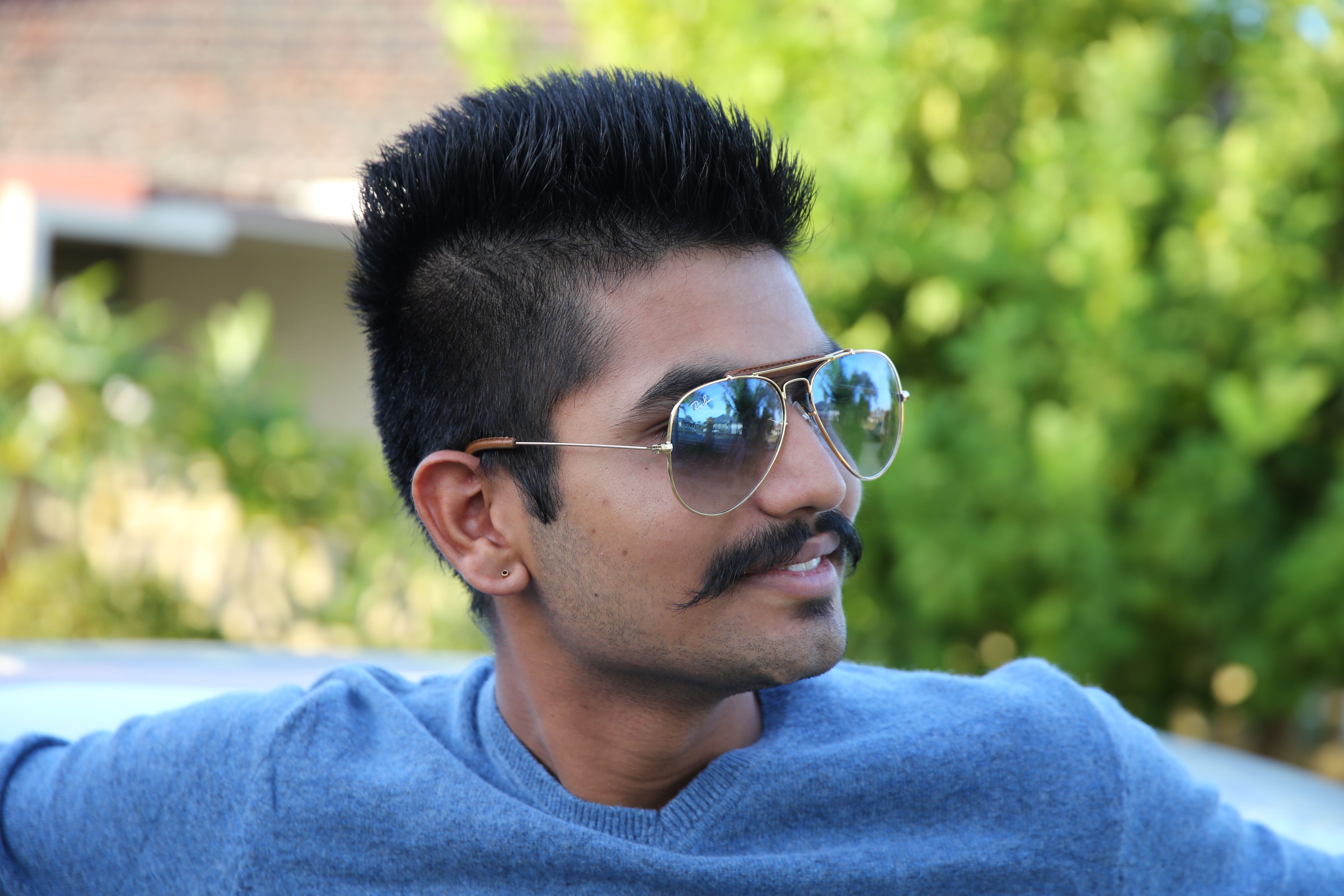 Portrait of a man with sunglasses and mustache enjoying a sunny day outdoors.
