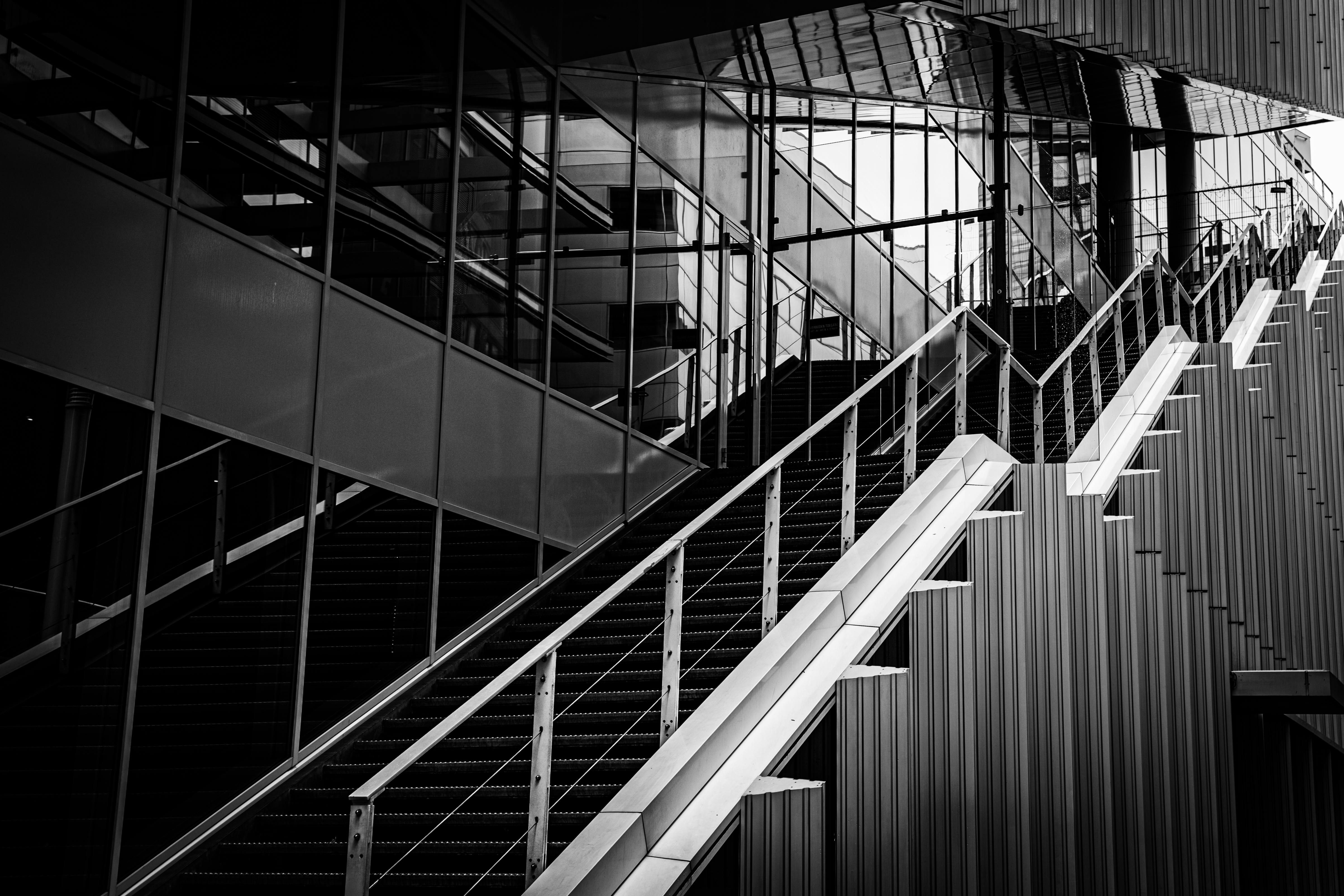 Free Dynamic black and white photo of a modern architectural staircase with reflective surfaces. Stock Photo