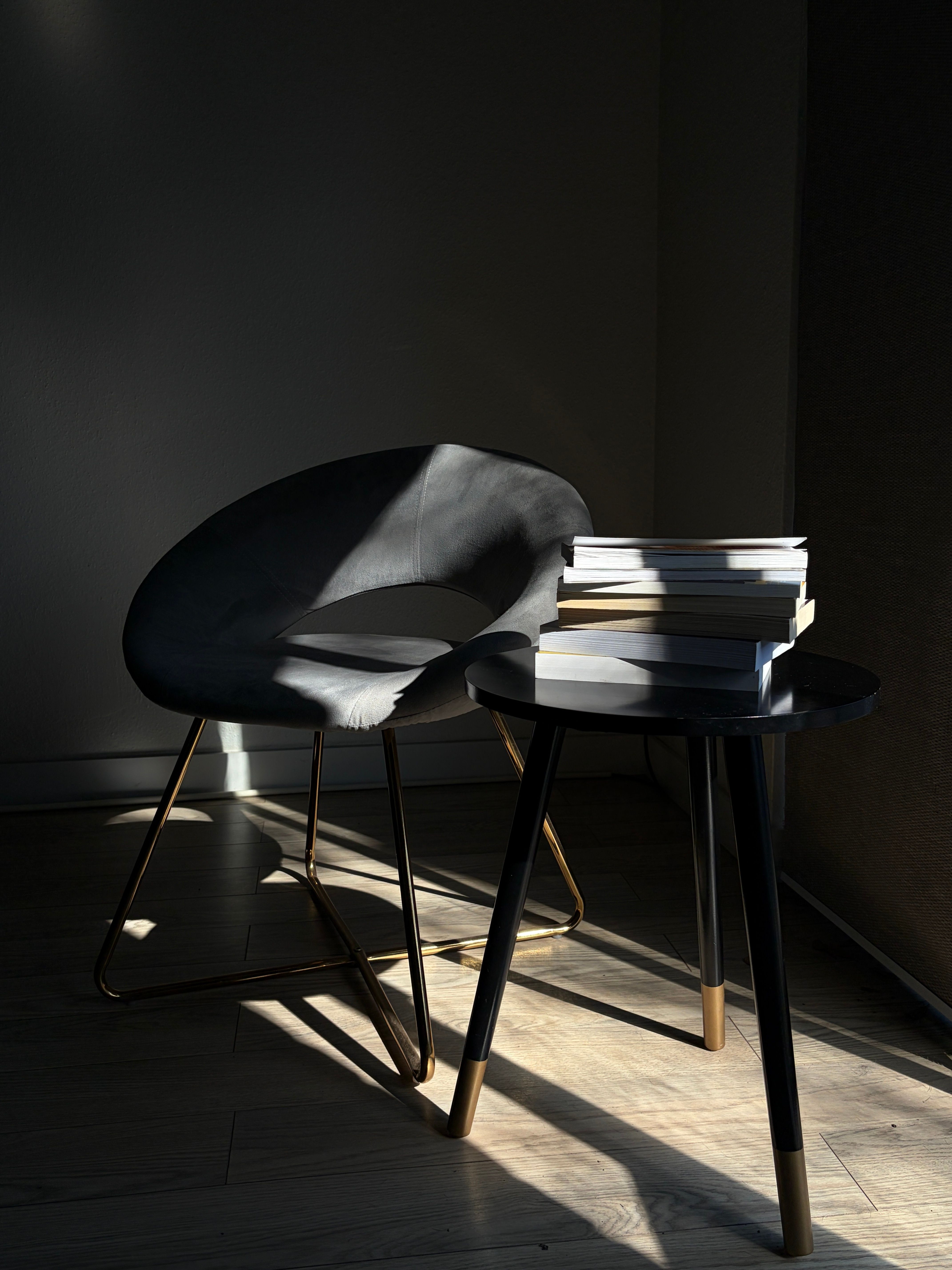 A minimalist setup with a modern chair and books bathed in sunlight creating a serene ambiance.