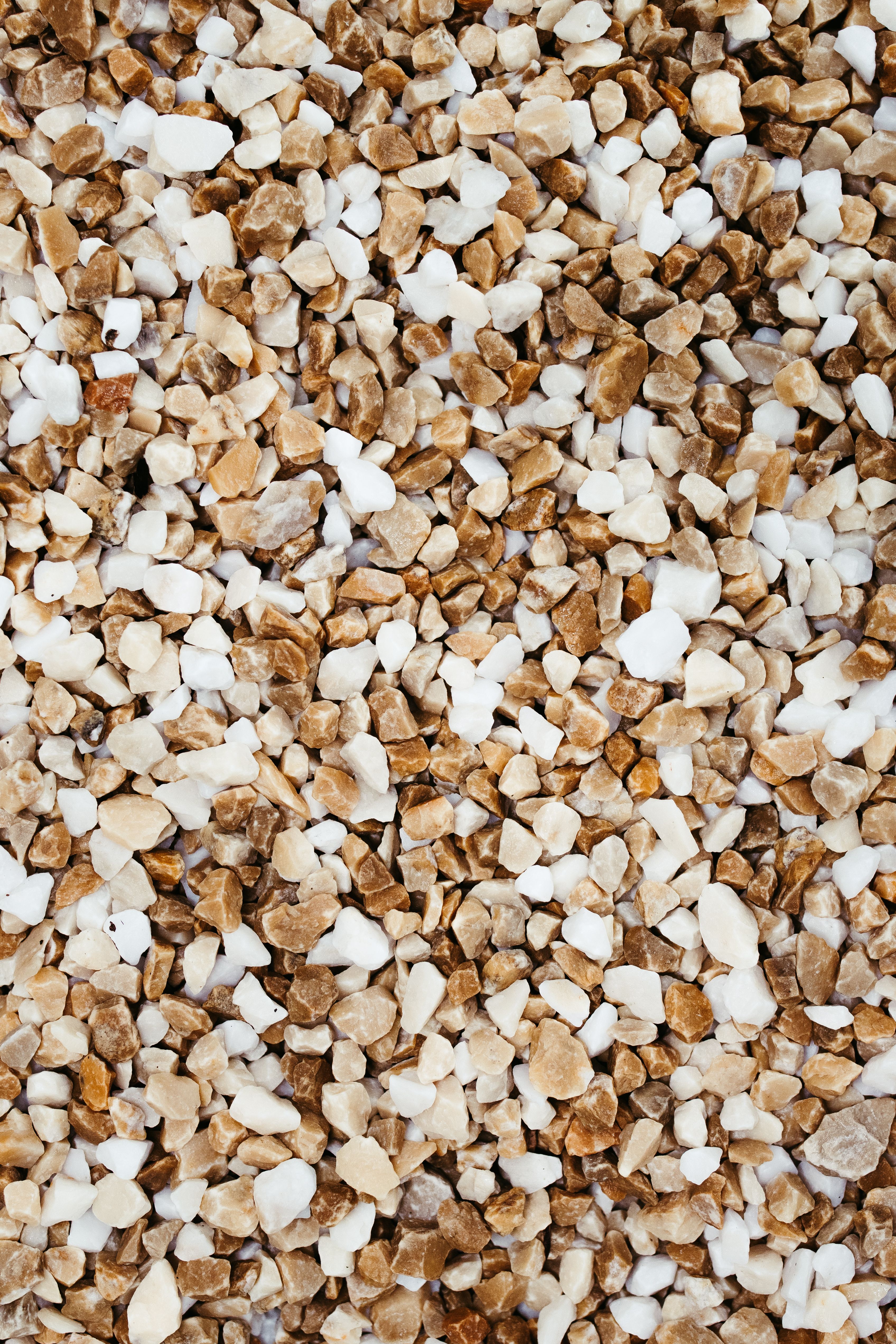 Gratis Primo piano di ciottoli di ghiaia marroni e bianchi che formano uno sfondo dalla texture naturale. Foto a disposizione