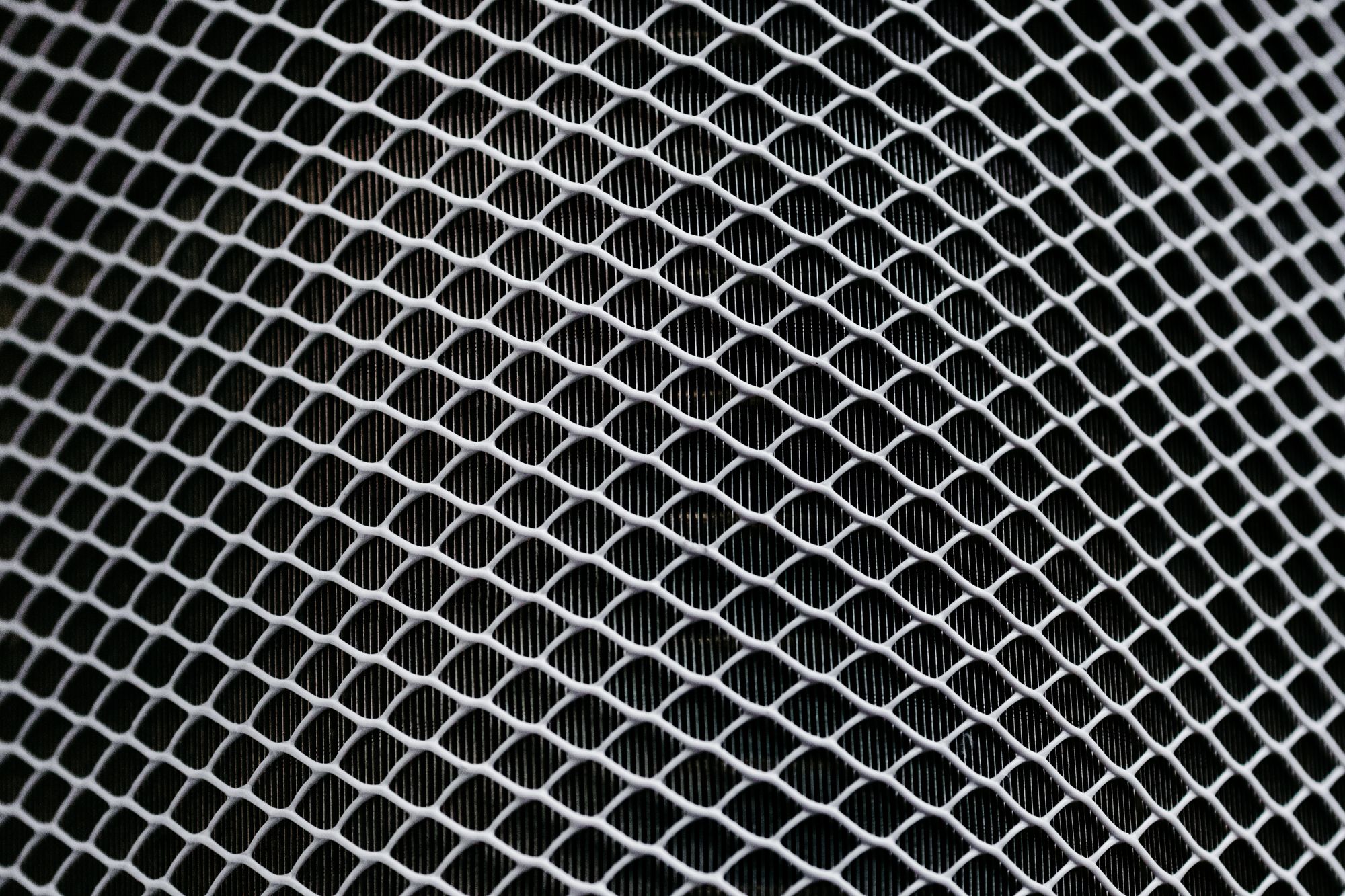 Detailed texture of industrial metal mesh with geometric patterns and shadows.