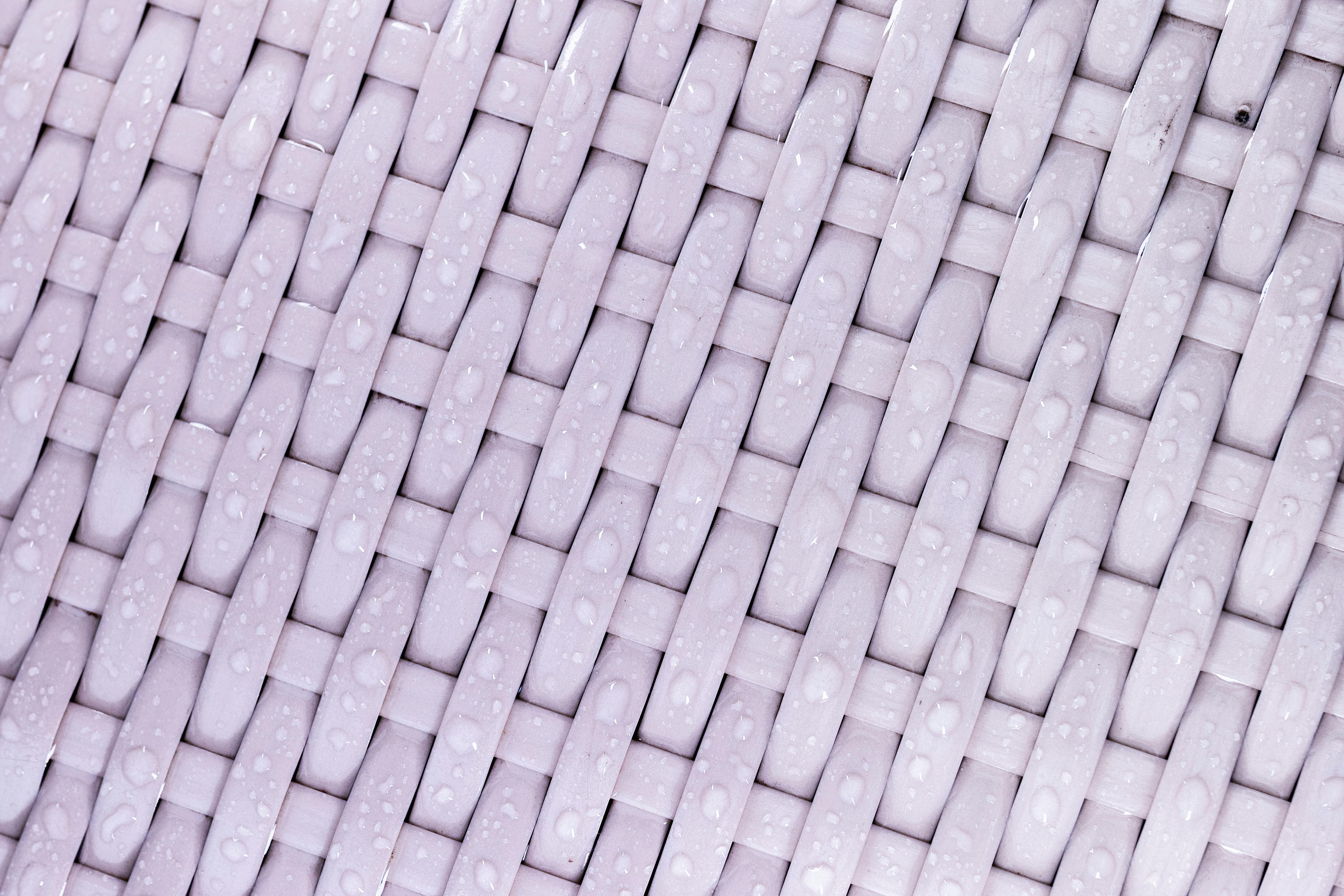 бесплатная Детальный крупный план тканой поверхности с каплями воды, демонстрирующий текстуру и узор. Стоковое фото