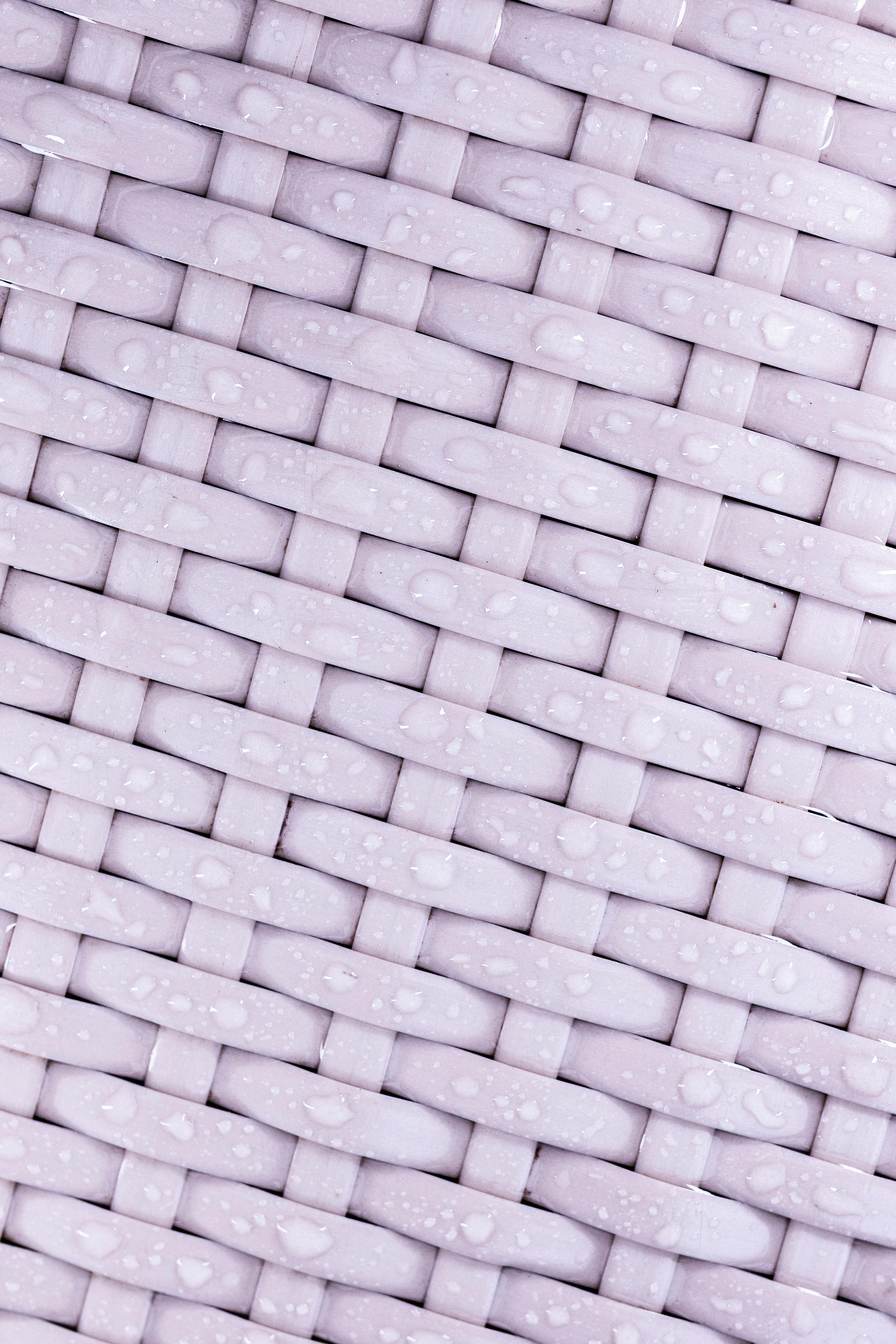 Ücretsiz Su damlacıkları ve pastel tonlarla dokunmuş bir kumaşın yakın çekim görüntüsü, karmaşık desenleri sergiliyor. Stok Fotoğraflar