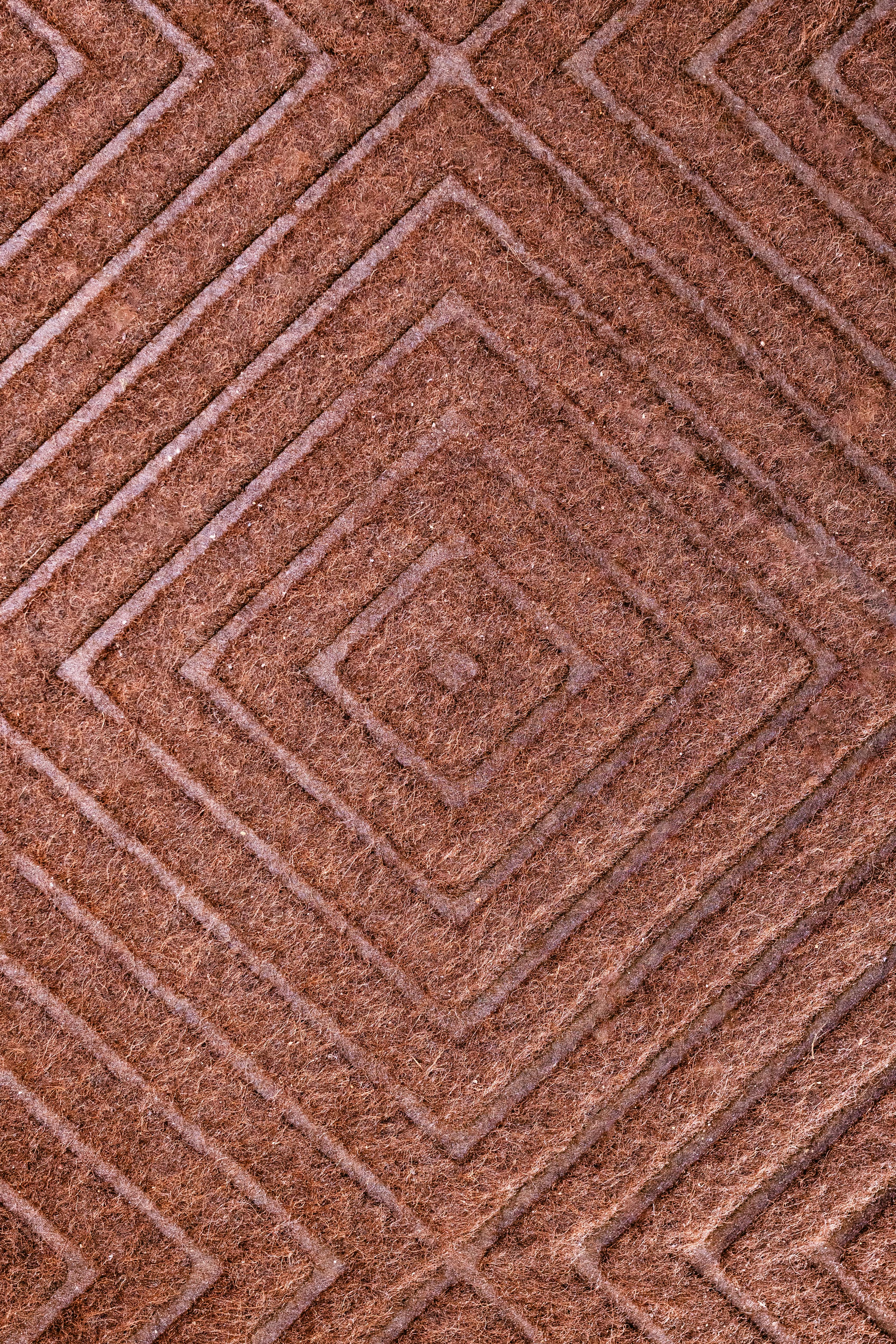 Free A detailed close-up view of a geometric patterned brown carpet texture, perfect for backgrounds. Stock Photo