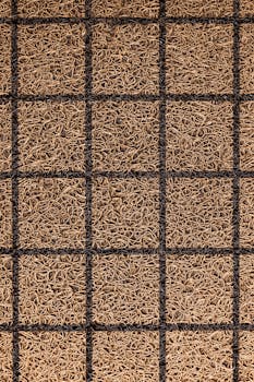 Close-up of a brown coir doormat with a black grid pattern, showcasing detailed texture.