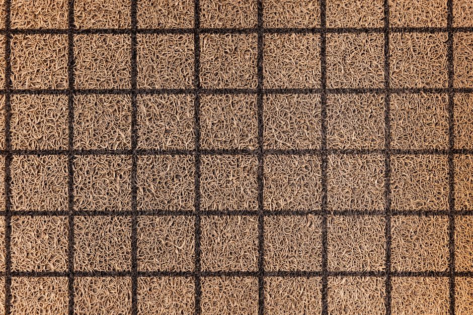 Overhead view of a textured woven coir doormat with a grid pattern.