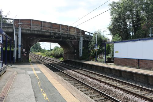 Free Empty railway station in Holmes Chapel, England with tracks and bridge on a sunny day. Stock Photo