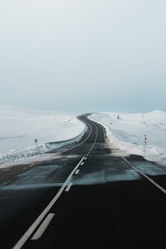 Scenic winter road winding through a snowy landscape in Kars, Türkiye, captured in serene daylight.