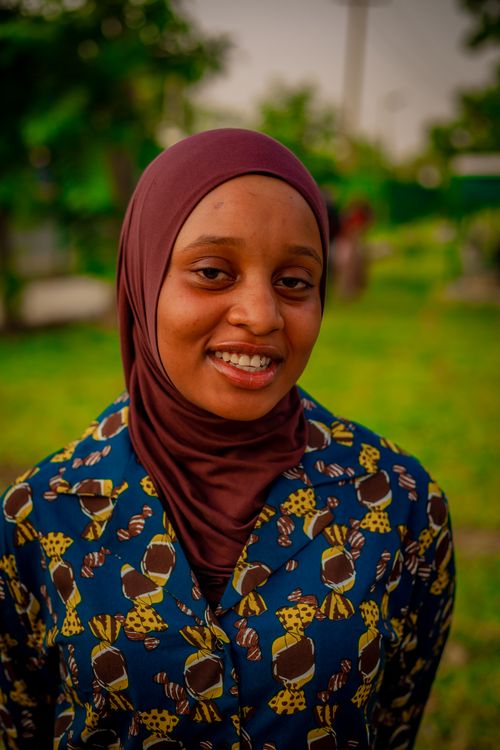 Free A young woman in a patterned outfit smiles warmly while standing outdoors. Stock Photo