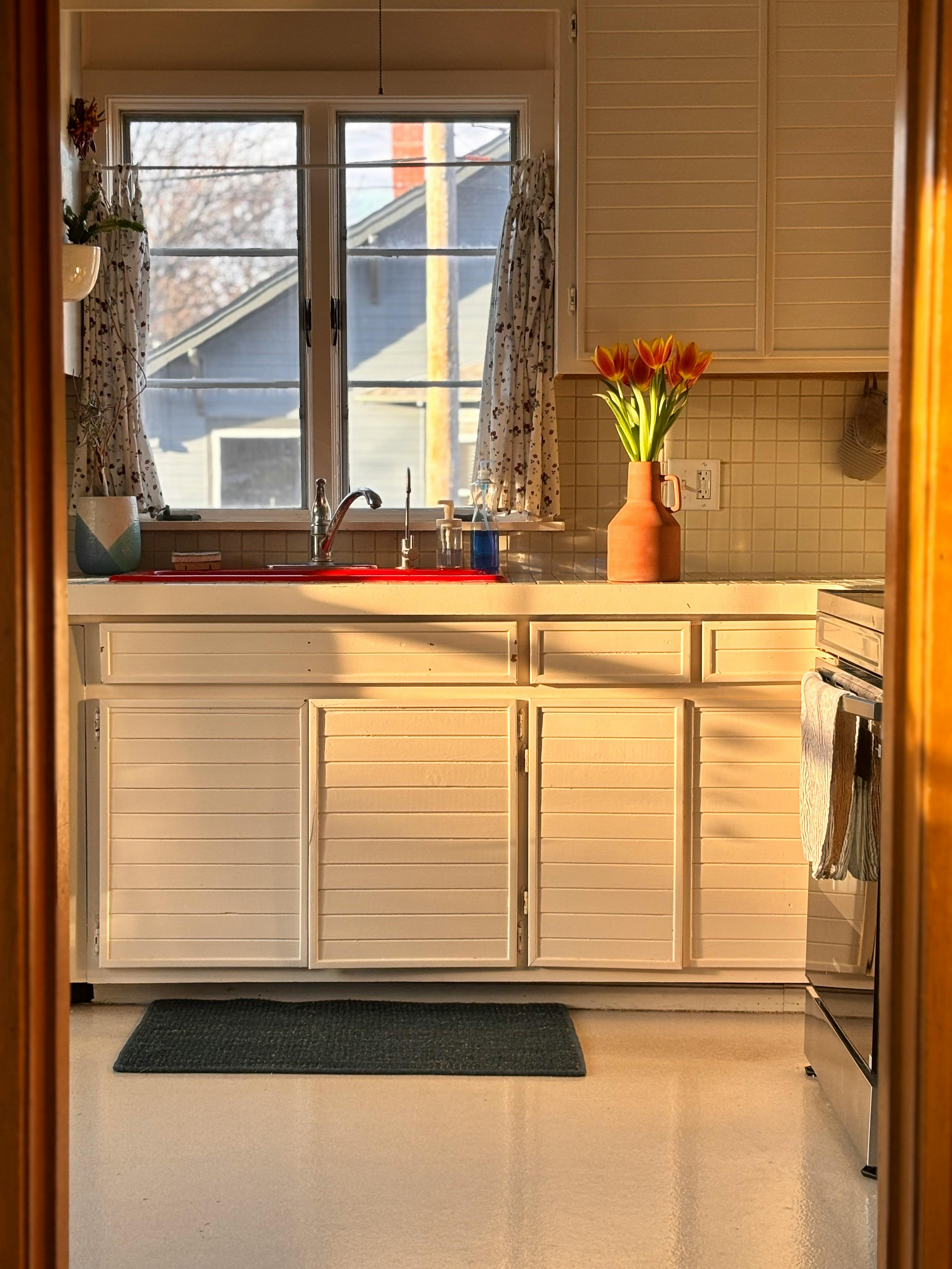 бесплатная Уютная и располагающая к отдыху кухня, залитая солнечным светом, с тюльпанами на столешнице. Стоковое фото