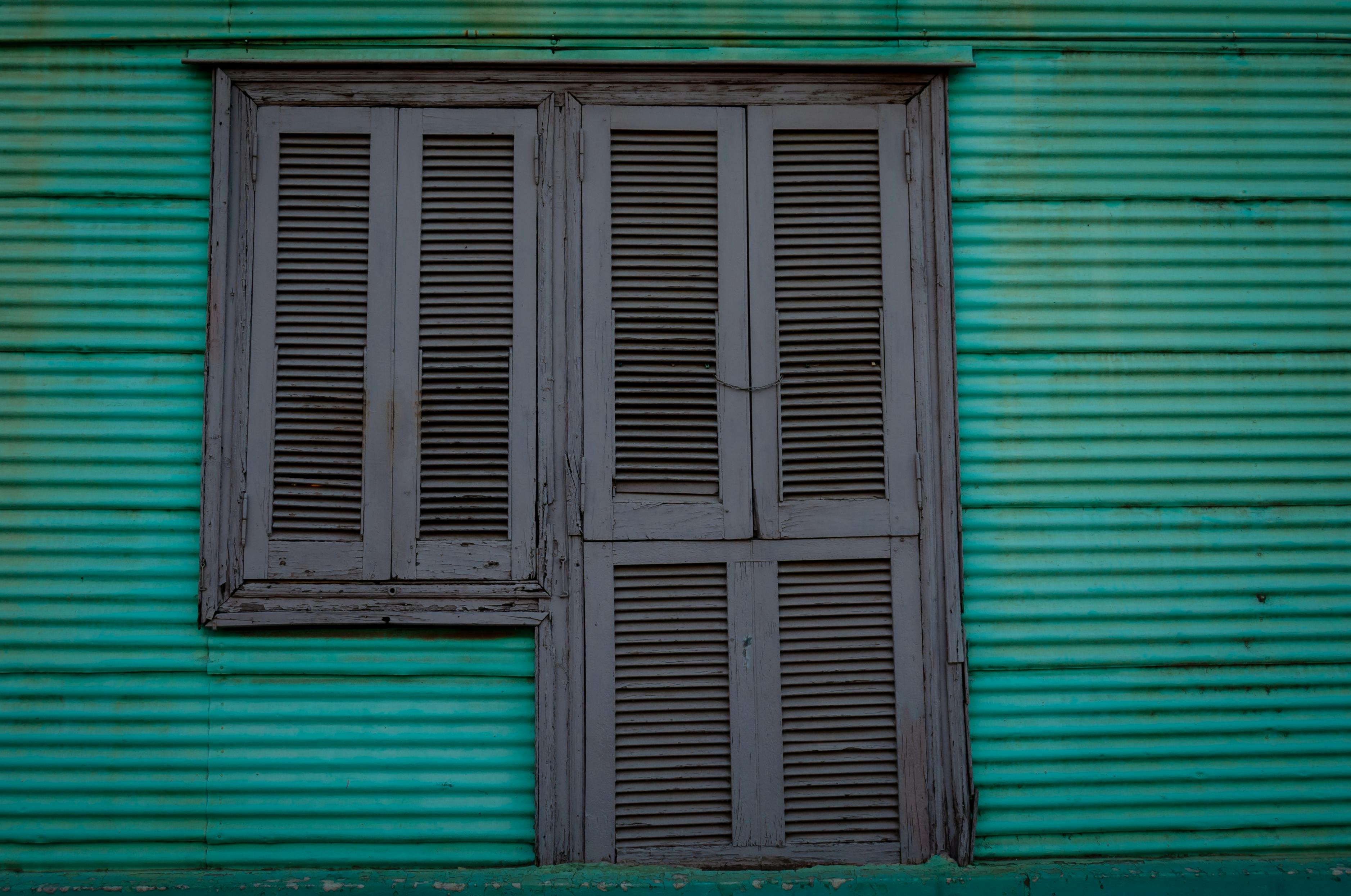 Ücretsiz Dokulu turkuaz bir duvara yerleştirilmiş, rustik bir estetik yaratan, eski tarz ahşap panjurlu bir pencerenin yakın çekim görüntüsü. Stok Fotoğraflar
