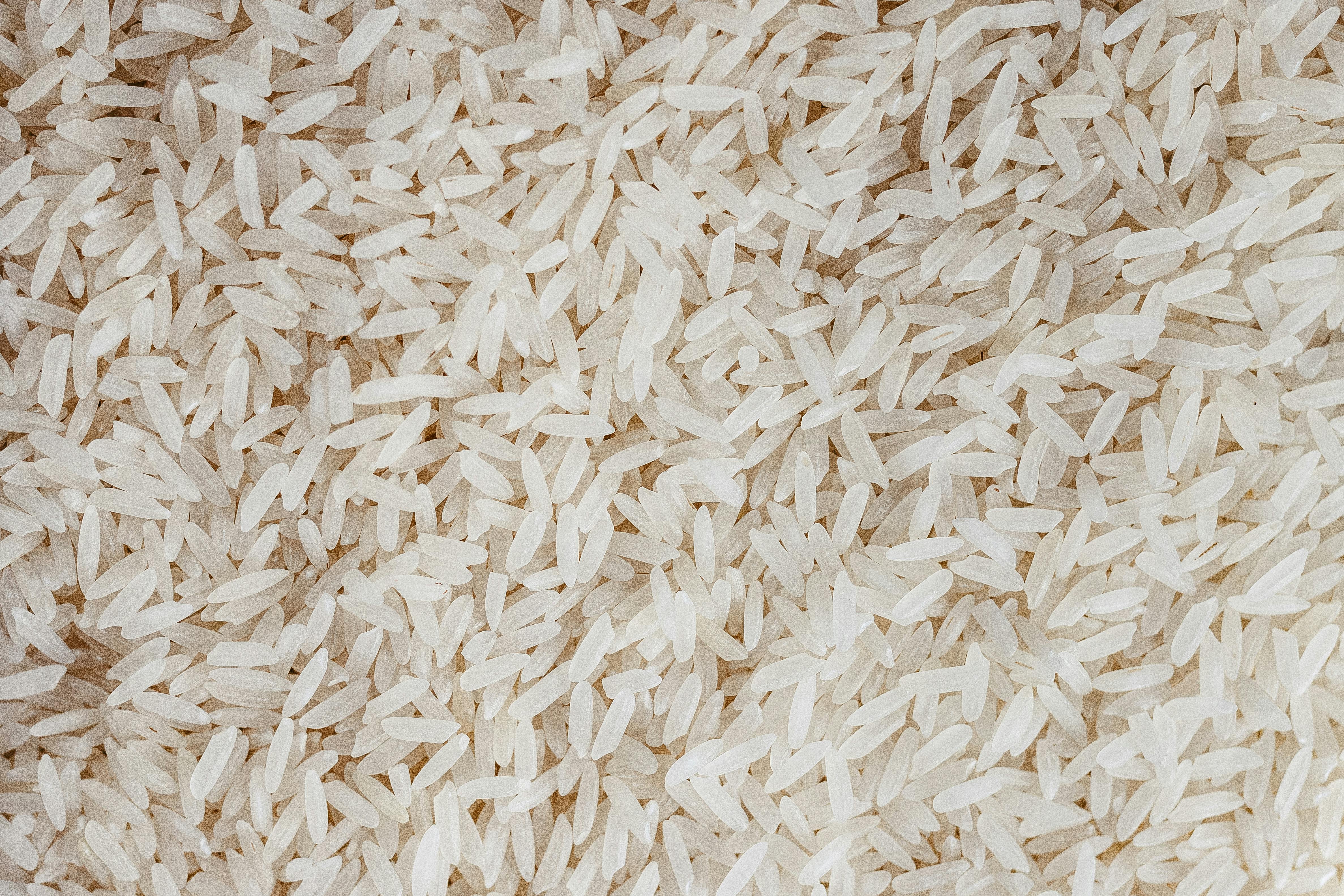 Free Detailed texture of uncooked white rice grains, perfect for food-related content. Stock Photo