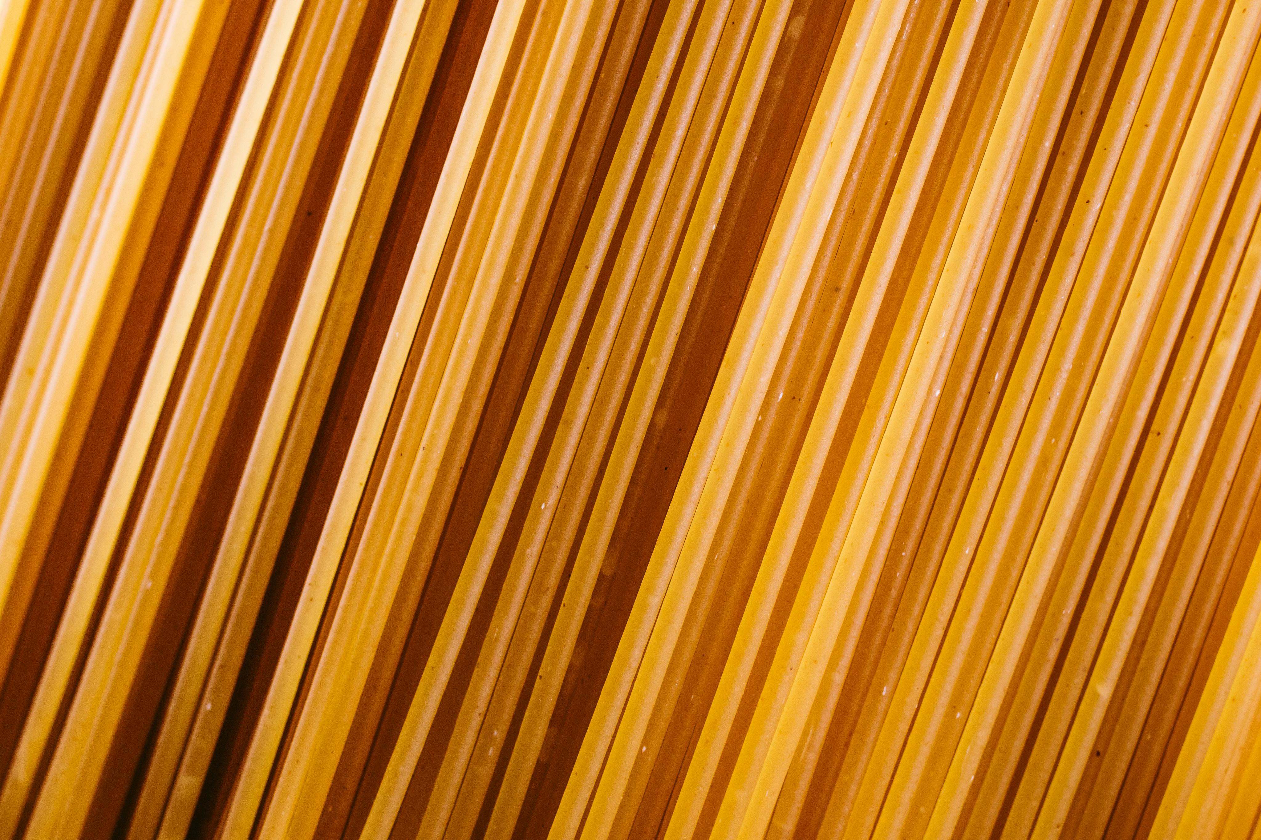 無料 鮮やかな黄色と質感を持つ、調理されていないスパゲッティパスタのクローズアップ斜めビュー。 写真素材