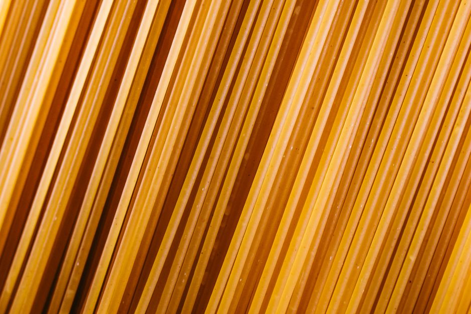 Fotomural Vista diagonal de primer plano de pasta de espaguetis cruda con textura y color amarillo vibrante.
