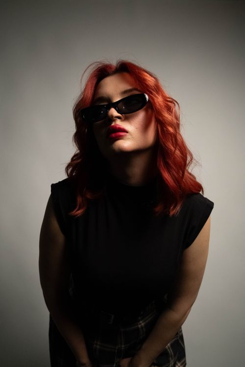 Free Moody portrait of a woman with red hair and sunglasses, evoking a bold, confident style. Stock Photo