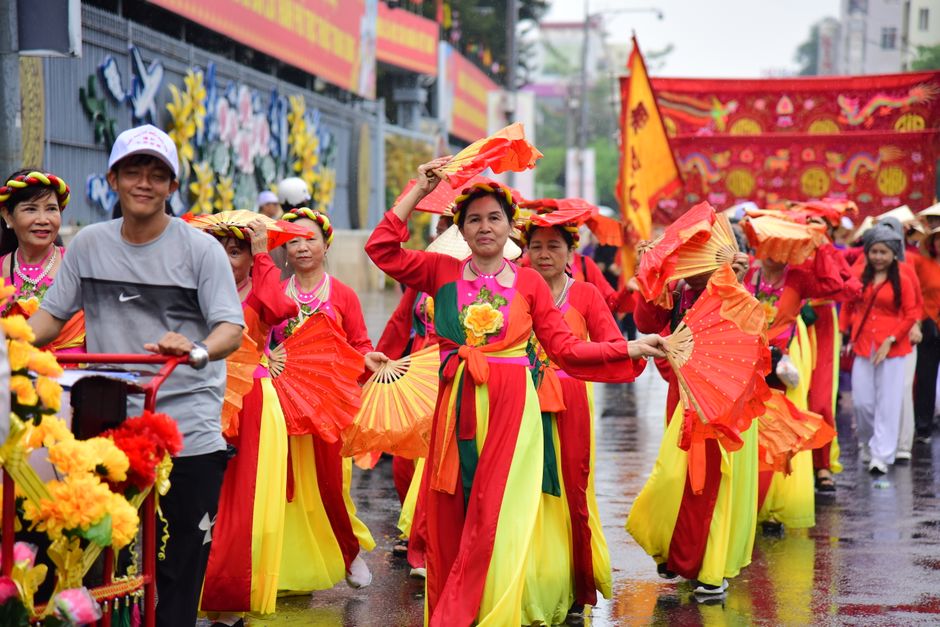 A vibrant parade featuring dancers in traditional attire with fans, celebrating culture outdoors.