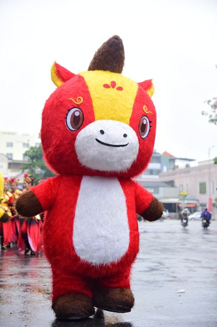 A vibrant cartoon horse mascot entertaining a crowd during an outdoor street parade.