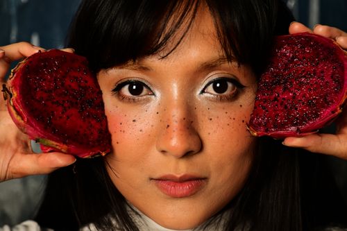 Free A woman's face framed by vibrant dragon fruit halves, showcasing natural beauty and exotic fruit. Stock Photo