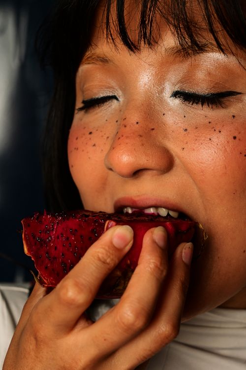 Free Close-up of a woman savoring a fresh dragon fruit slice, eyes closed, expressing delight. Stock Photo