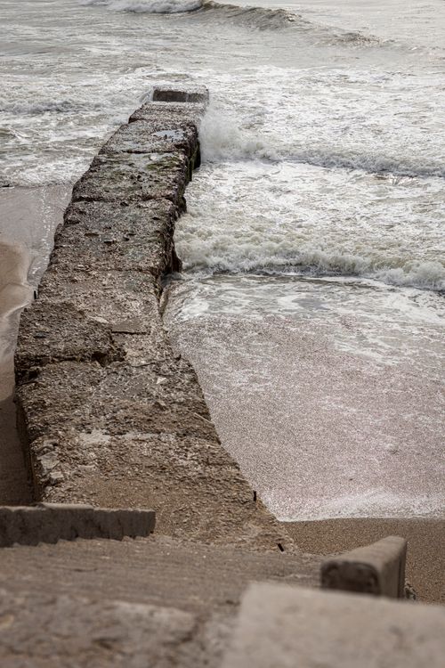 Free Waves hit a rugged sea wall on a cloudy day at Miramar Beach, Buenos Aires. Stock Photo